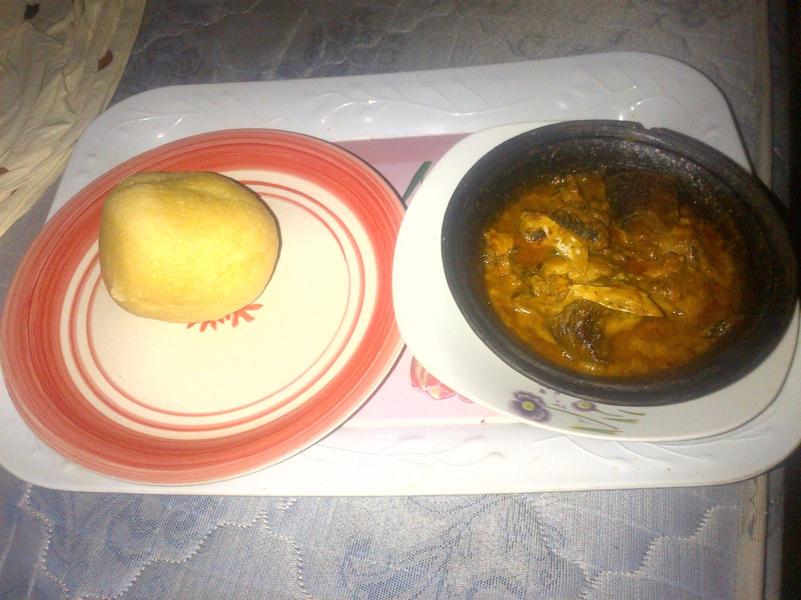 Fresh-fish banga soup in a black clay pot, served beside a round of eba